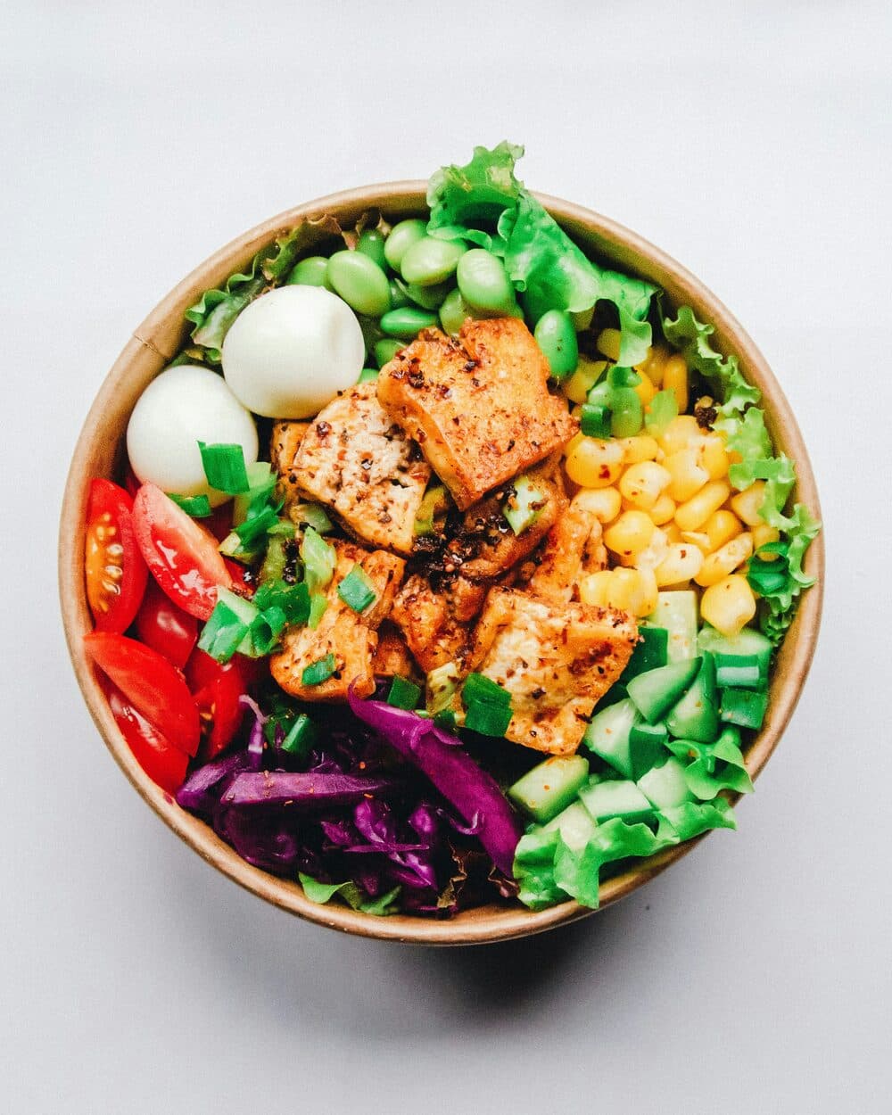 Bowl med stekt tofu, edamame, majs, tomat, gurka och ägg