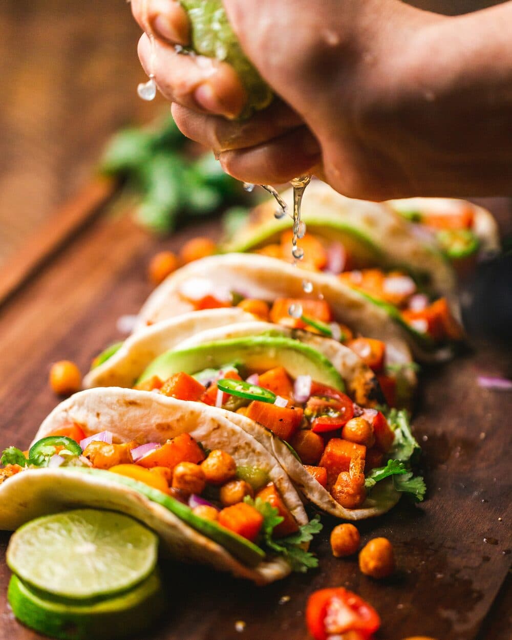 Tacos fyllda med kikärtor, sötpotatis och avokado medan lime pressas över